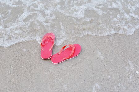 flip flops on beach with wave sandy beach sea at the ocean - top viewの写真素材