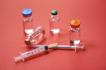 Medicine bottles glass for syringe injection needle on red background / Medication drug bottle equipment medical tool for nurse or doctorの写真素材