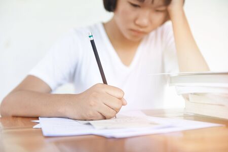 exam stress / education young female college in class taking notes and using a pencil sitting...