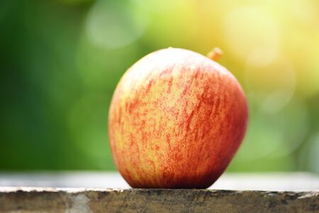 Fresh red apple on wooden table and nature green background in the summer fruit