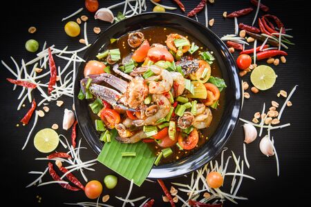 Seafood salad spicy with fresh shrimp crab cockles served on black plate fresh vegetables herbs and spices ingredients with chilli tomato peanut garlic green papaya shredded - Som tum Thai menu Asianの写真素材