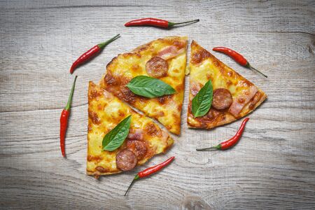 Pizza on wooden tray and chilli basil leaf top view / delicious tasty fast food italian traditional pizza cheese with Mozzarella , Smoked pork sausage , Pineapple ham on topping sauceの写真素材