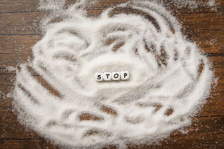 no sugar stop text blocks with white sugar on wooden background / suggesting dieting and eat less...