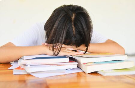 exam stress / education young female college in class taking notes and using a pencil sitting learning concept stressed student girl asian take the exam final  and sleeping on booksの写真素材