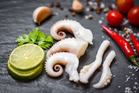squid salad with lemon herbs and spices on dark background top view / Tentacles octopus cooked appetizer food hot and spicy chilli sauce seafood cooked served on black plate in the restaurantの写真素材