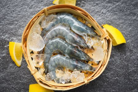 raw shrimps on bamboo steamers with ice spices lemon on the dark plate / fresh shrimp prawns at restaurant or seafood marketの写真素材