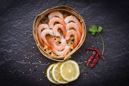 fresh shrimps on bamboo steamers with spices lemon chilli on the dark plate / boiled peeled shrimp prawns cooked in the seafood restaurantの写真素材