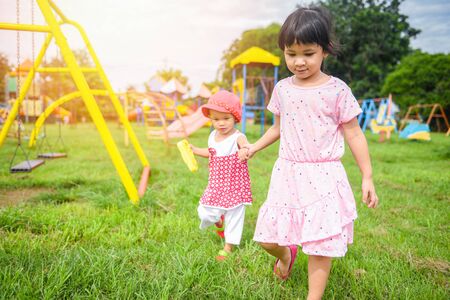 Children having fun little girl holding hand together with love playing outside Asian kids happy in the garden park with playground / International Childrenâs Dayの写真素材
