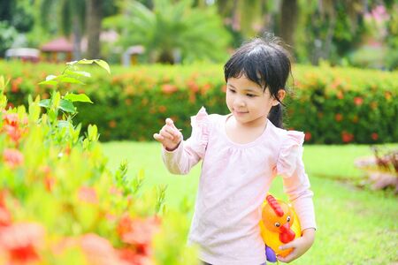 Child smile having fun playing outside girl happy in the garden park with flower tree / International Childrenâs Day Asian kidの写真素材