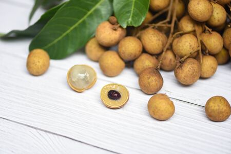 Longan fresh tropical fruit and green leaf in Thailand / Dimocarpus longan and peel exotic fruits on white wooden backgroundの写真素材