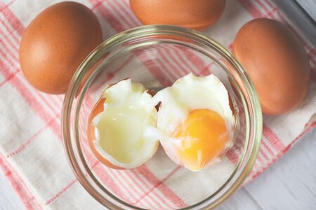 boiled egg on glass bowl and fresh eggs on the table background top view / Soft boiled eggsの写真素材