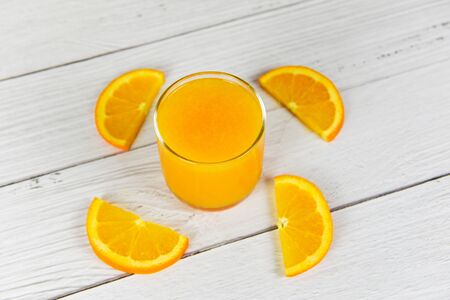 Orange juice in the glass and fresh orange fruit slice on wooden tableの写真素材