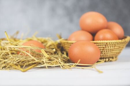 Fresh egg on basket and straw with wooden table background top view / Raw chicken eggs collect from the farm products natural eggsの写真素材