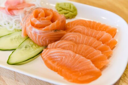 Japanese food raw sashimi salmon fillet with vegetable cucumber and wasabi in the restaurant, Salmon sashimi menu set Japanese cuisine fresh ingredients on plate, selective focusの写真素材