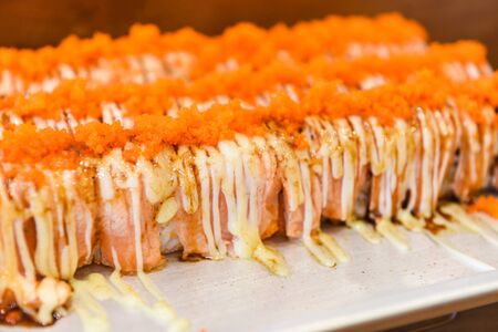 Salmon sashimi japanese food sushi  with Tobiko egg cream sauce on salmon fillet in the restaurant / Sashimi sushi menu set Japanese cuisine fresh ingredients on tray , top view selective focusの写真素材