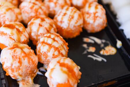 Sushi menu set Japanese cuisine fresh ingredients on tray / Japanese food sushi ball with cream sauce and tobiko egg is orange (flying fish roe) in the restaurantの写真素材