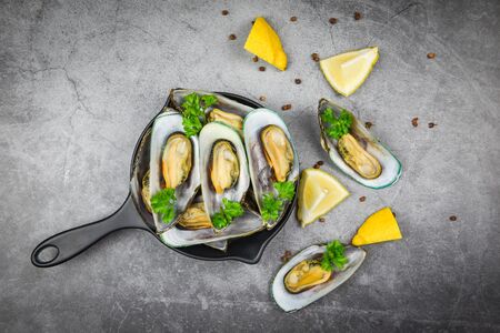 Mussels with herbs in pot with lemon parsley tomato in the table setting / Steamed mussels green shell served seafood delicious on dining table restaurantの写真素材