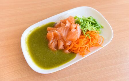 Japanese food raw sashimi salmon fillet with carrot celery seafood sauce in the restaurant / salmon salad menu set Japanese cuisine fresh ingredients on plate , selective focusの写真素材