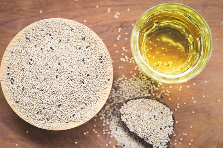 sesame seeds in a wooden bowl and spoon with sesame oil in glass , top viewの写真素材