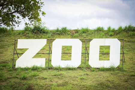 White sign of zoo on field slope hill / The Zoo