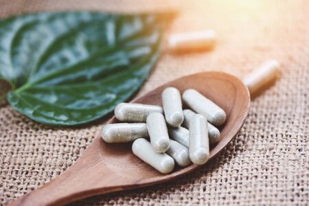 Herbal Medicines / Natural herb capsules on wooden spoon and green leaf on sack background , selective focusの写真素材