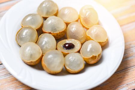Longan fresh tropical fruit in Thailand / Dimocarpus longan peel exotic fruits on white plate on...