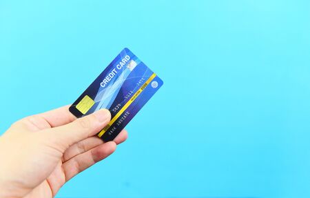 hand holding credit card on blue background / payment online shopping paying with credit card...