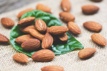 Almonds on green leaf / Close up almond nuts natural protein food and for snack on sack background , selective focusの写真素材