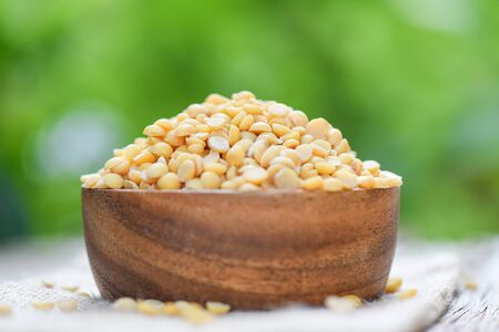 Soybean in a wooden bowl with nature green background / Peeled Split Soybean or Soya Bean without...
