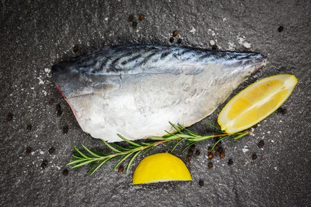 Fresh fish fillet sliced for steak or salad with herbs spices rosemary and lemon / Raw fish seafood on black plate background , Longtail tuna , Eastern little tuna fillet ingredients for cooking food の写真素材