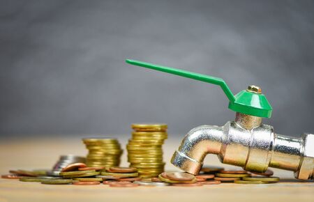 faucet on money coin wood background / water savings and faucet money fall conceptの写真素材
