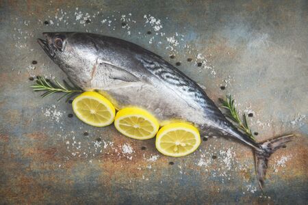 Fresh fish with herbs spices rosemary and lemon / Raw fish seafood on black plate background top view , Longtail tuna , Eastern little tuna fishの写真素材