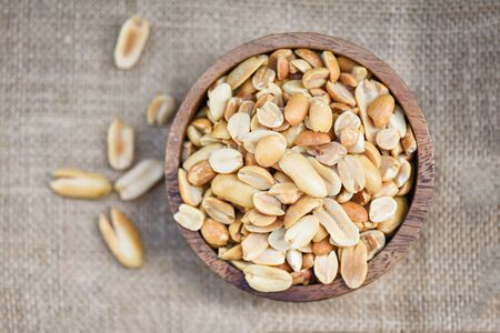 salted peanut as a food or snack / Roasted peanuts on a wooden bowl and sack background