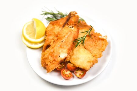 fried fish fillet sliced for steak or salad cooking food with herbs spices rosemary and lemon / tilapia fillet fish crispy served on white plate の写真素材