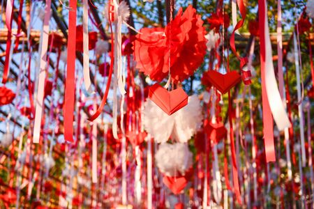Red heart paper cut and ribbon hanging on the love tunnel heart shaped outdoors in the event valentine dayの写真素材