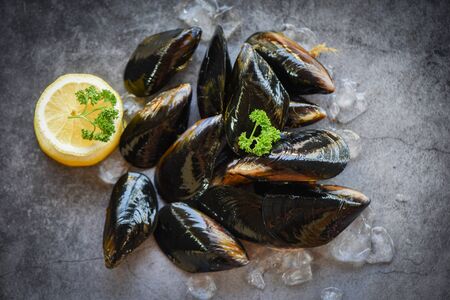 Raw Mussels with herbs lemon and dark plate background / Fresh seafood shellfish on ice in the restaurant or for sale in the market mussel shell food  の写真素材