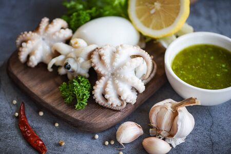 Squid salad spices lemon garlic chili sauce on wooden cutting board background / cooked food squids octopus or cuttlefish at seafood restaurant の写真素材