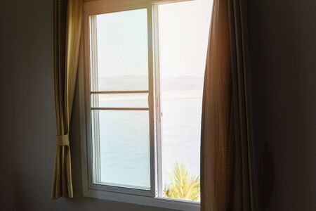 window view sea beach and mountains in the bed at bedroom morning and sunlight / window glass with...
