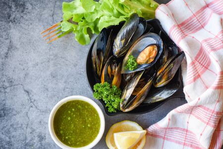Cooked Mussels with herbs lemon and dark plate background / Fresh seafood shellfish on bowl and spicy sauce salad in the restaurant mussel shell foodの写真素材