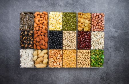 Box of different whole grains beans and legumes seeds lentils and nuts colorful snack background top view / Collage various beans mix peas agriculture of natural healthy food for cooking ingredientsの写真素材