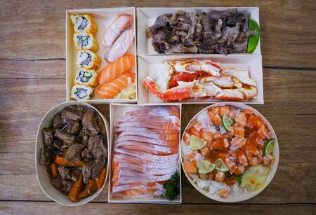 Japanese food sushi roll rice with salad salmon sashimi braised beef crab legs in the restaurant sushi menu set / Japanese cuisine fresh ingredients mix various types on wood table , top viewの写真素材