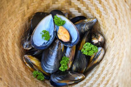 Mussels with herbs lemon on cook steamer food background / Fresh seafood shellfish in the restaurant mussel shell food on bamboo steamer basketの写真素材