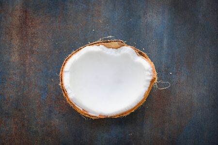 half of coconut fruit for coconut milk on dark table background, top view