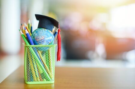 Graduation hat on earth globe model  global education study concept / Education learning and back to school with graduation cap on a pencil case on the table in the library backgroundの写真素材