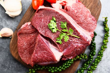 Raw beef meat on wooden cutting board on the kitchen table for cooking beef steak roasted or grilled with ingredients herb and spices , Fresh beef animal proteinの写真素材