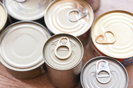Various canned food in metal cans on wooden background , top view / canned goods non perishable food storage goods in kitchen home or for donationsの写真素材