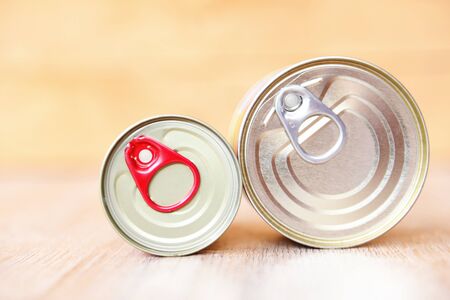Canned food in metal cans on wooden background / canned goods non perishable food storage goods in kitchen home or for donationsの写真素材