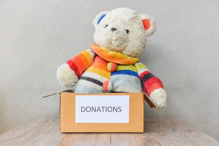 Donations box with teddy bear doll wooden table background / donate toy conceptの写真素材