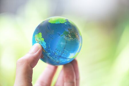 The world in the hand with nature background / hand holding globe environment green planet save the earth day concept の写真素材