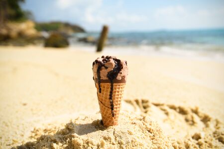 Ice cream cone on sand beach background / Melting ice cream on beach sea in summer hot weather ocean...